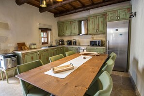 Une cuisine avec une table en bois, des chaises vertes, un réfrigérateur en acier inoxydable et divers appareils électroménagers.