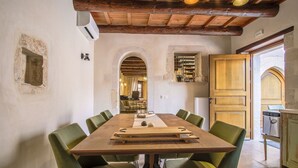 A dining area with a wooden table and green chairs, a kitchen area with wooden cabinets, and a rustic ceiling with exposed beams. - Villa with garden, inneryard and terrace with a view to Talean Mountains (Melidoni Rethymni)