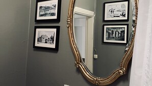 A bathroom with a large ornate mirror, three framed black and white photographs on the wall, and a white tiled sink. - Agardhs Pensionat (Sveg)