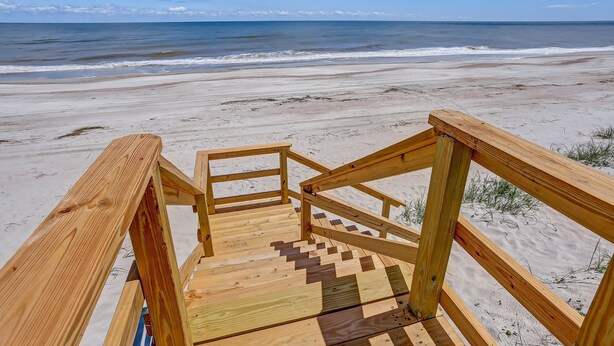 A wooden staircase leading to a sandy beach with the ocean in the background. - Oceanfront Beach House with Spacious Backyard by RedAwning (Fernandina Beach)