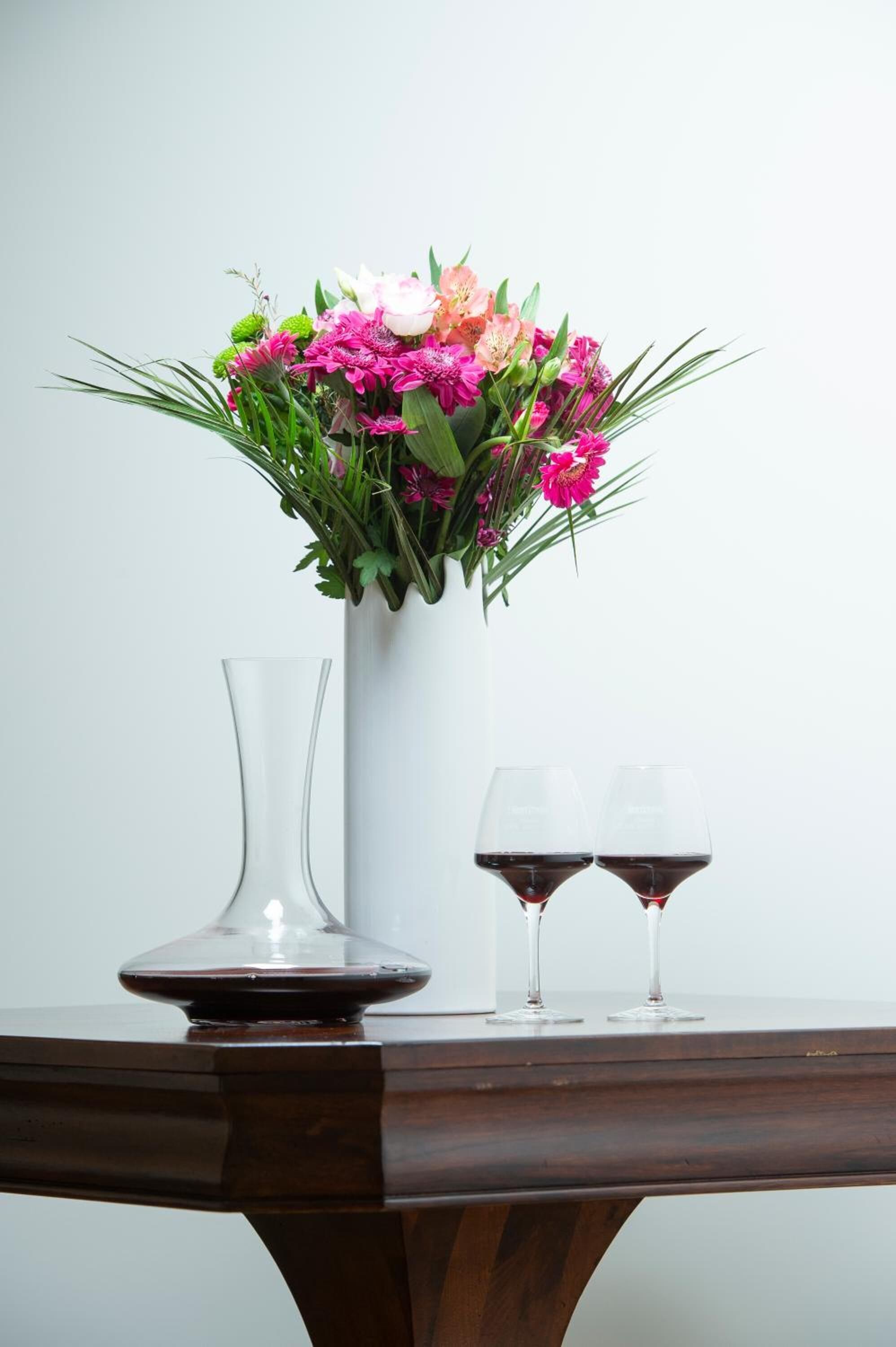 Une table avec un vase de fleurs et deux verres à vin.