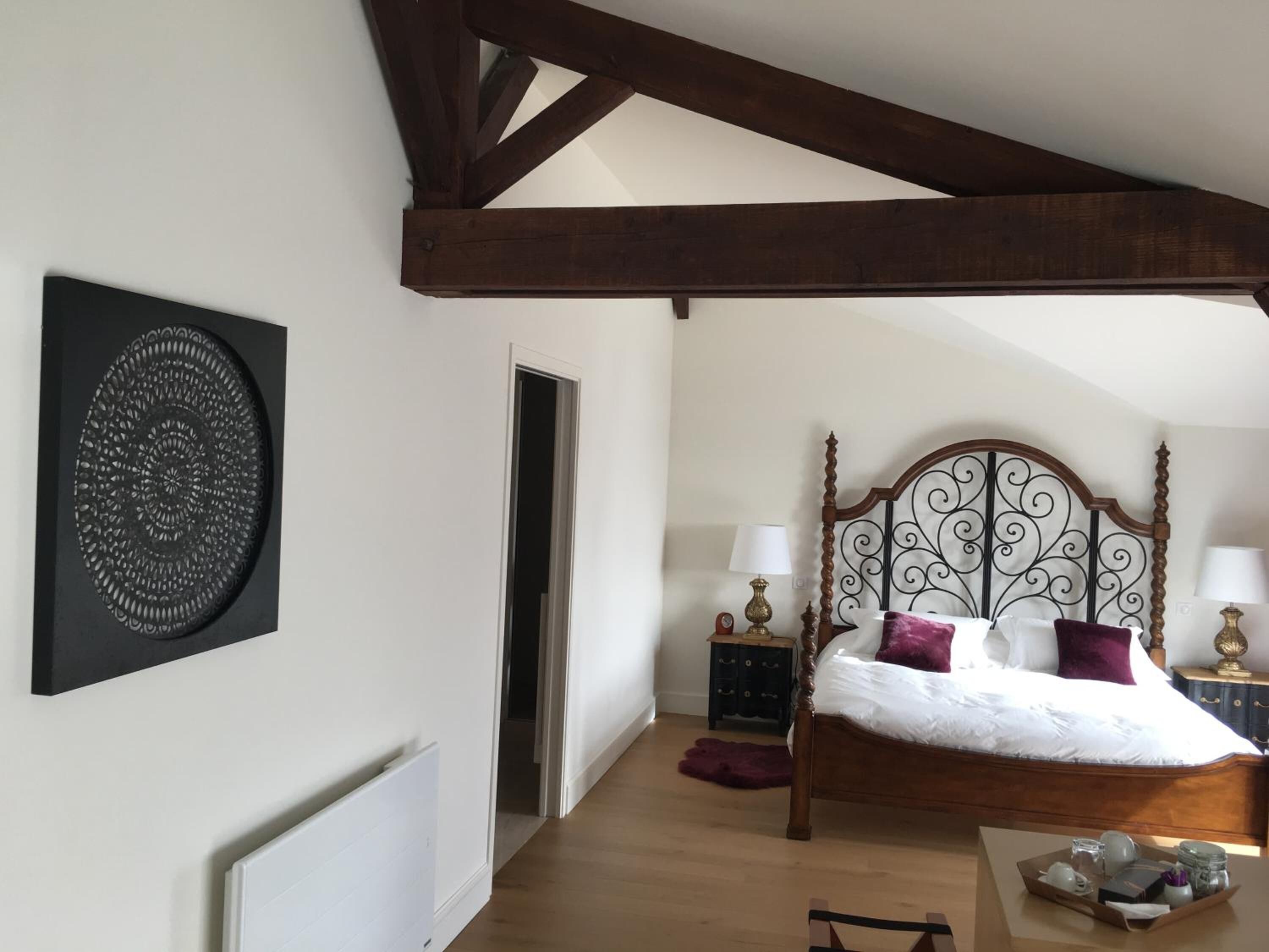 A bedroom with a wooden bed, a decorative wall piece, a nightstand, and a dresser.
