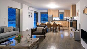 A modern kitchen with wooden cabinets, a dining area with a table and chairs, and a living room with a sofa and coffee table.