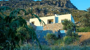 A modern building with a stone facade, large windows, and a view of a mountainous landscape.