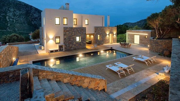 A modern house with a swimming pool, stone walls, and outdoor furniture.