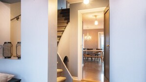 En trappe fører op til et spiseområde med en lysekrone og møbler i træ.