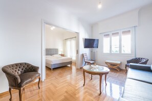 A spacious living room with a large bed, a TV, and a seating area with a table and chairs.
