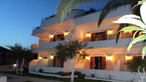A multi-story hotel with balconies, a well-maintained lawn, and a pathway leading to the entrance. - Ocean Front Studios (Kefalonia)