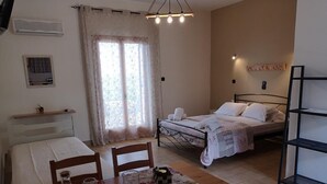 A bedroom with a bed, bedside table, and a small window with curtains. - Ocean Front Studios (Kefalonia)