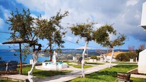 A well-maintained garden with a swimming pool, a pergola, and a view of the sea. - Ocean Front Studios (Kefalonia)