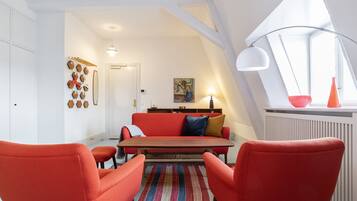 A modern living room with a red sofa, matching armchairs, a wooden coffee table, and a colorful rug.
