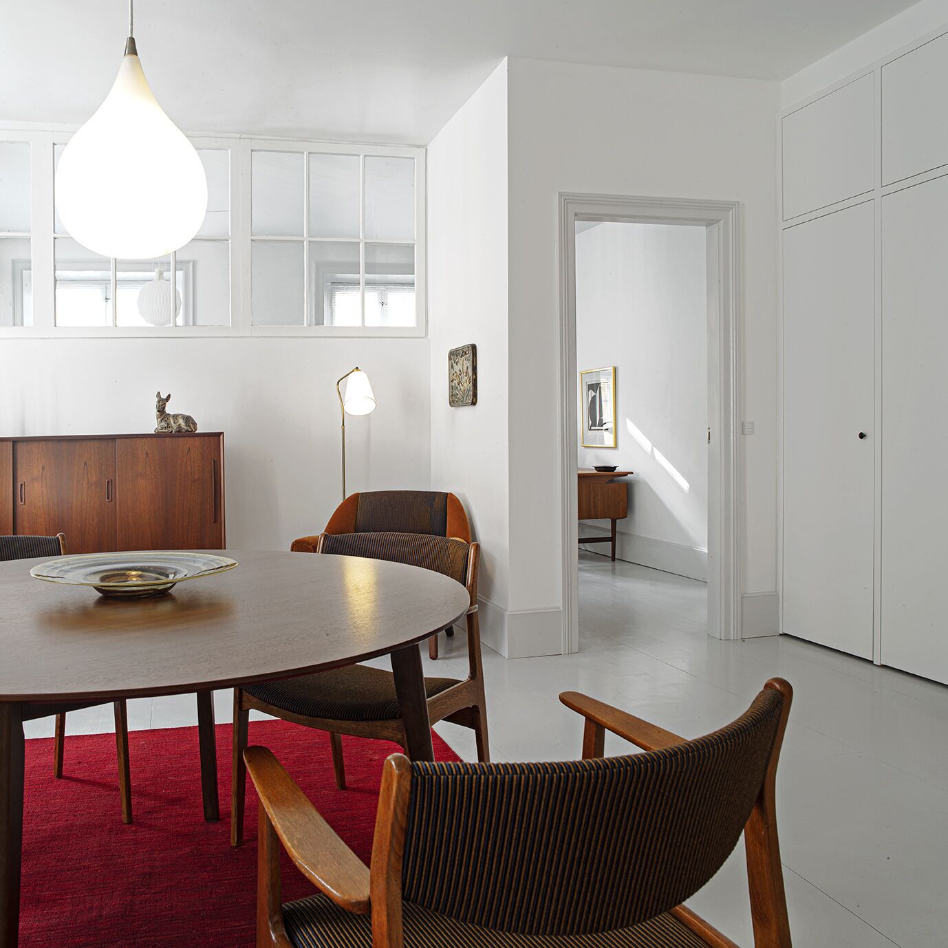 Een moderne eetruimte met een ronde tafel, stoelen en een rood tapijt.