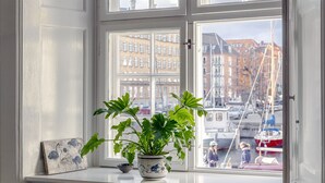 A window with a view of a marina and buildings. - Kanalhuset (Copenhagen)