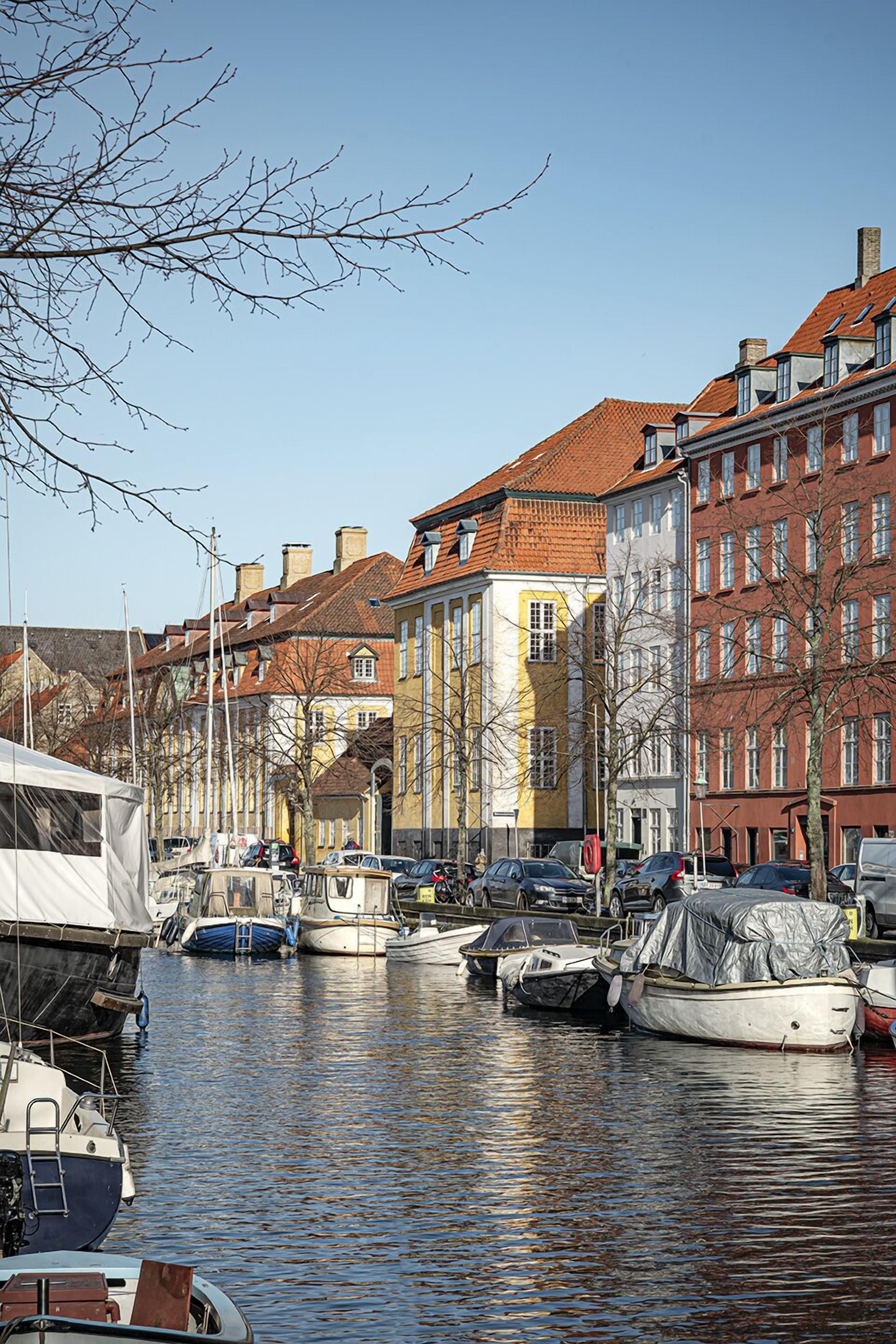 A canal with boats docked along the sides, surrounded by buildings with red and yellow facades.