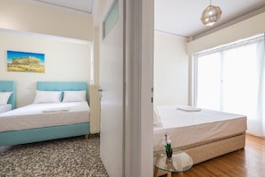 A hotel room with a bed, a small table with a plant, and a painting on the wall. - Acropolis View Paradise Apartments (Athina)