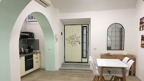 A modern kitchen with a built-in stove, a coffee maker, and a microwave. There is a dining area with a white table and chairs. - Casa Doria - Vatican Museums (Roma)
