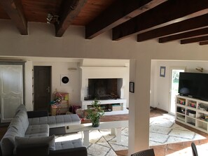 A living room with a sectional sofa, a fireplace, a television, and a bookshelf.