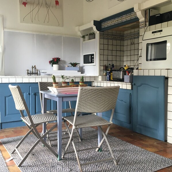 A kitchen with blue cabinets, a white countertop, and a patterned rug.