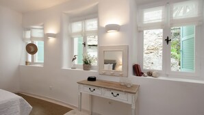 A bedroom with a white dresser, a mirror, and a window with a view of the outside. - White Jasmine Cottage (Corfu)