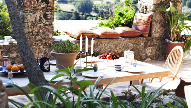 A rustic outdoor dining area with a stone table, chairs, and potted plants. - White Jasmine Cottage (Corfu)