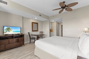 A hotel room with a bed, a TV, a desk, and a ceiling fan. - Lockout Unit ~ Private Foyer ~ Community Pool (Miramar Beach)
