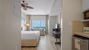 A hotel room with a bed, a desk, a television, and a view of the ocean. - Studio Unit ~ Community Pool ~ Family Friendly (Miramar Beach)