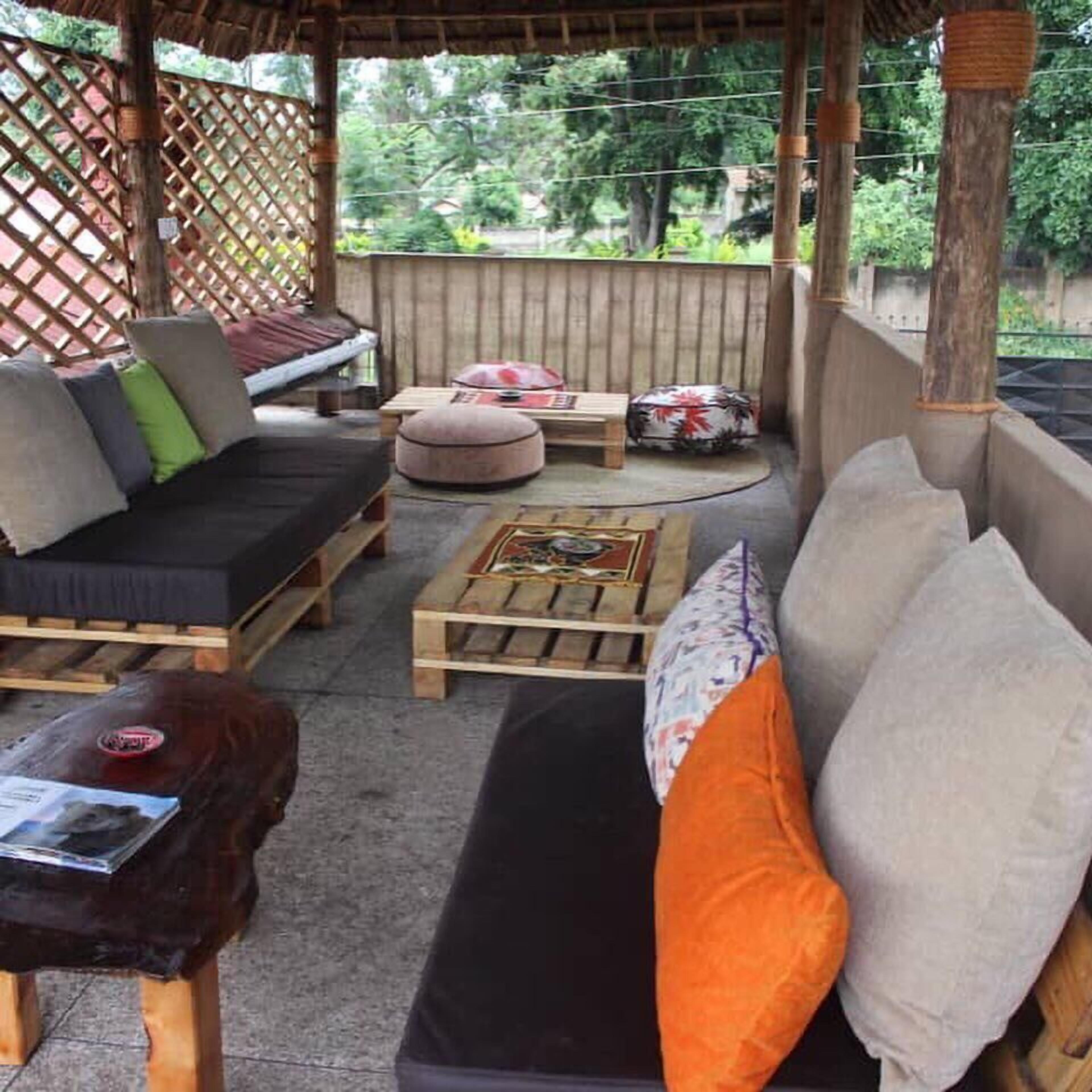 An outdoor seating area with a wooden bench, a sofa with cushions, and a small table.