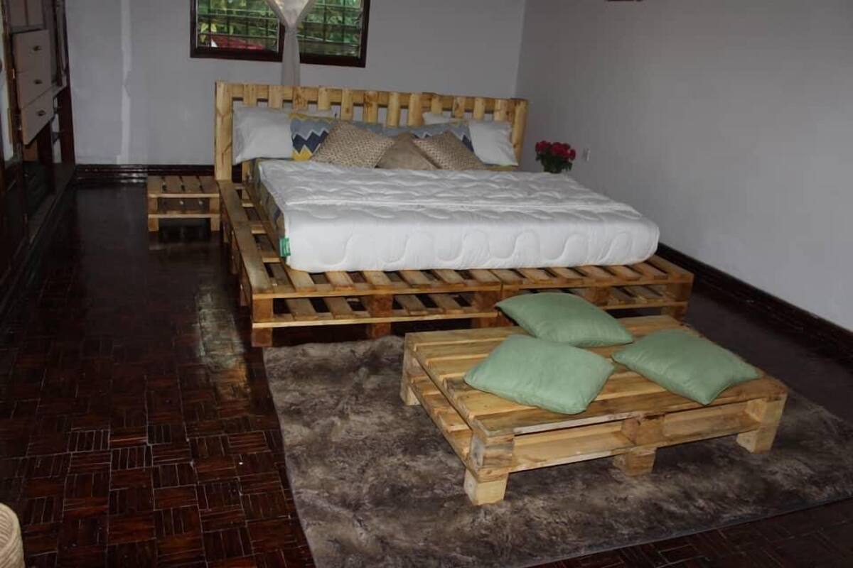 A room with a wooden bed, a small wooden bench, and a fur rug.