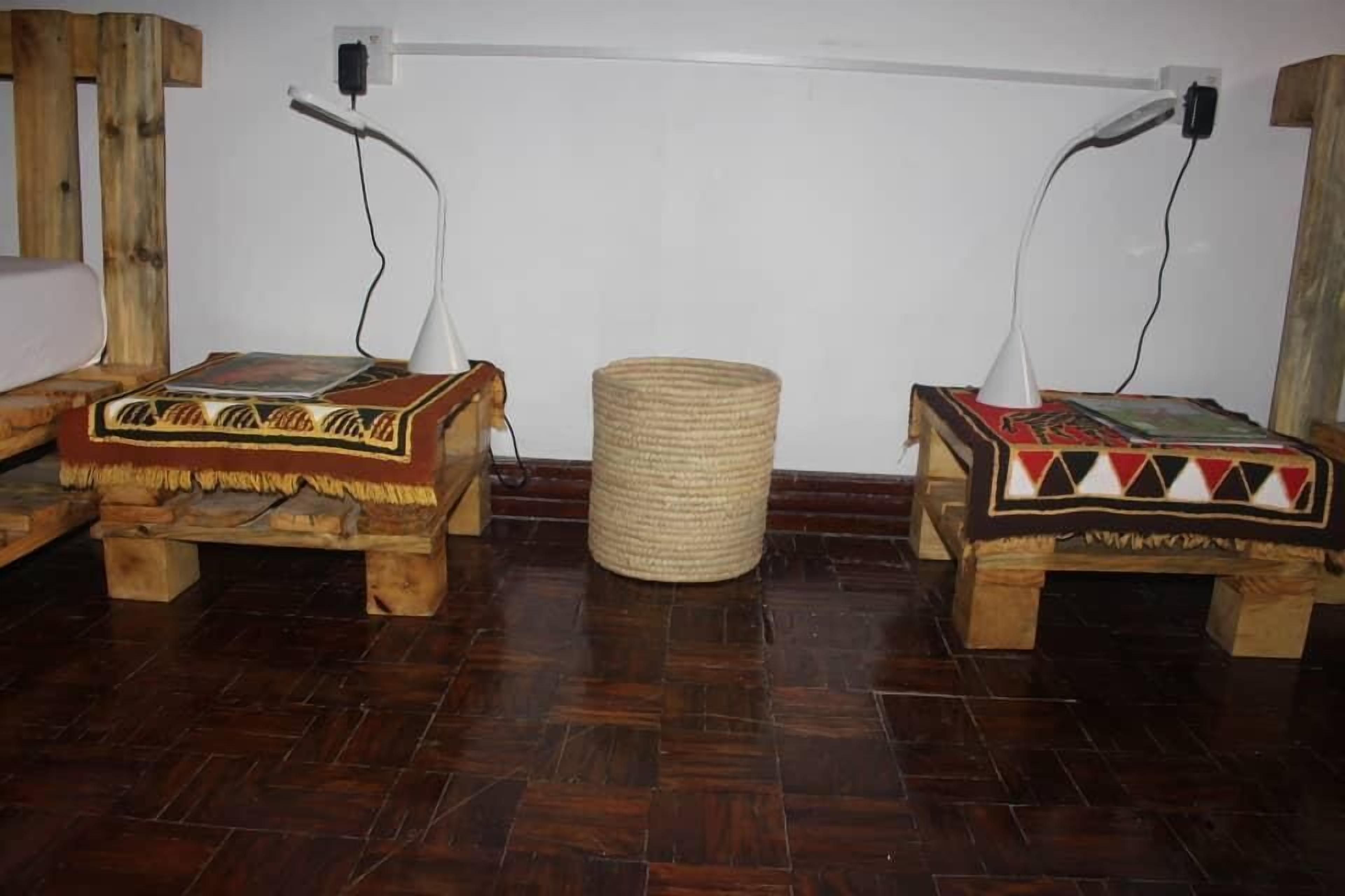 Two wooden benches with woven baskets, a woven stool, and a white wall with electrical outlets.