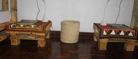 Two wooden benches with woven baskets, a woven stool, and a white wall with electrical outlets.