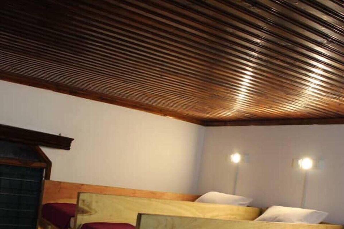 A room with bunk beds, wooden walls, and a sloped ceiling.