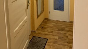 Un couloir avec deux portes, dont une avec une vitre dépolie et l’autre avec un panneau de verre bleu à texture.
