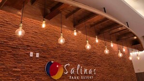 A brick wall with hanging light bulbs and a logo for Salinas Park Resort. - Condomínio Salinas Park Resort (Salinópolis)