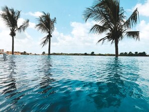 A swimming pool with clear blue water, surrounded by palm trees and a clear sky. - Condomínio Salinas Park Resort (Salinópolis)