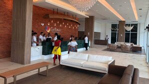 A hotel lobby with a reception desk, a large chandelier, and seating areas. - Condomínio Salinas Park Resort (Salinópolis)