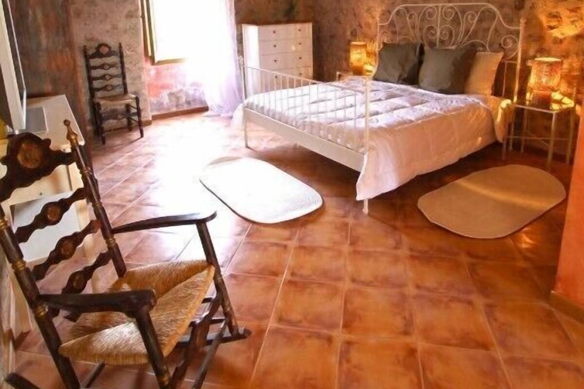 A bedroom with a bed, bedside tables, a rocking chair, and a window.