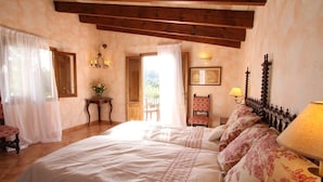 Un dormitorio con una cama grande, una silla, una mesa y una lámpara.