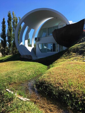 A modern building with a unique circular design, surrounded by a grassy area and trees.