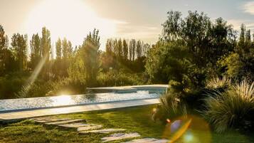 Un entorno tranquilo al aire libre con piscina, escalones de piedra y abundante vegetación.