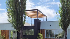 A modern house with a wooden deck leading to a pond, surrounded by trees. - La Escondida San Rafael - Cabañas (San Rafael)