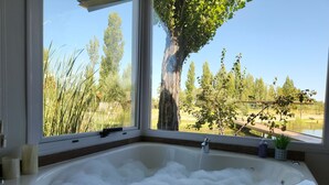 A corner bathtub with a view of a garden and trees. - La Escondida San Rafael - Cabañas (San Rafael)