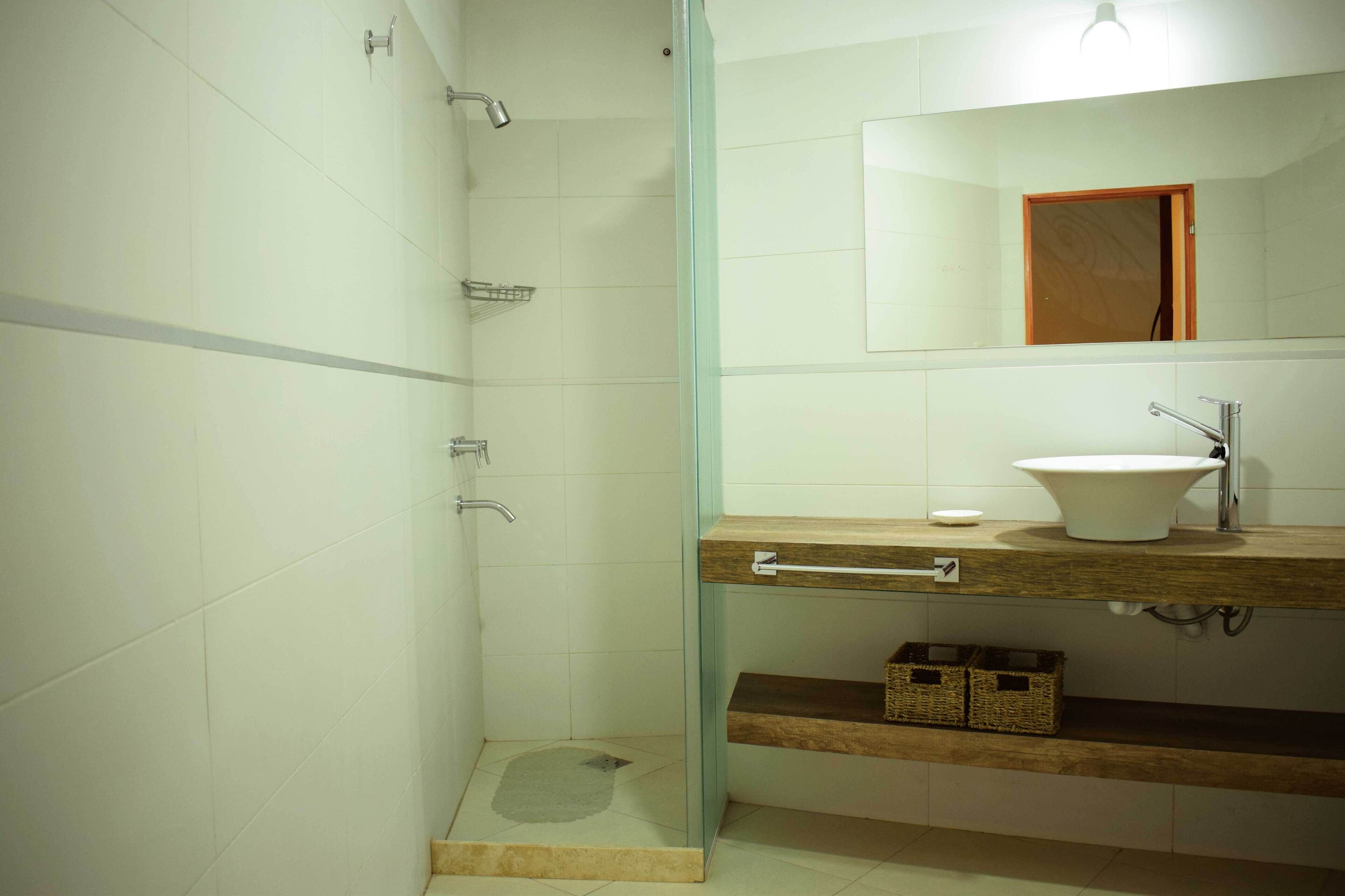 A bathroom with a glass shower enclosure, a wooden vanity with a sink, and a mirror above the vanity.