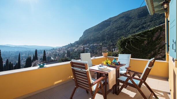 A balcony with a table and chairs, overlooking a mountainous landscape. - Harmony House (Corfu)