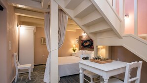 A bedroom with a bed, a white desk with a chessboard, a chair, a nightstand with a lamp, and a staircase. - Harmony House (Corfu)