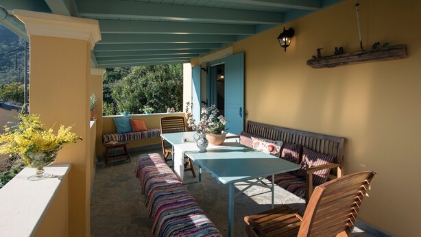 Une terrasse couverte avec une table, des chaises et un banc.