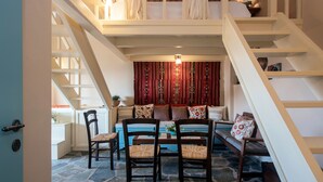 Une pièce chaleureuse avec un sol en pierre, un canapé bleu et un escalier.