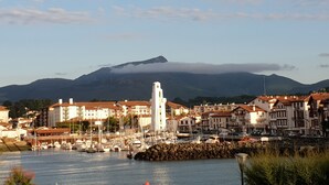 Eine Küstenstadt mit einem Hafen, Gebäuden mit roten Dächern und einem Berg im Hintergrund.