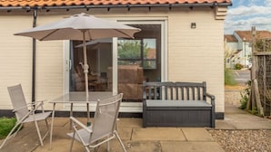 A patio with a table, chairs, and an umbrella. - Sea Breeze, Brancaster, Norfolk (Brancaster)