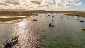 A river with boats and a boat docked on the shore. - Sea Breeze, Brancaster, Norfolk (Brancaster)
