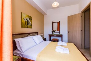 A hotel room with a bed, a desk, a mirror, and a door.